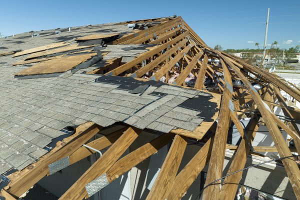 Damaged house roof with missing shingles after hurricane Ian in Florida. Consequences of natural disaster.